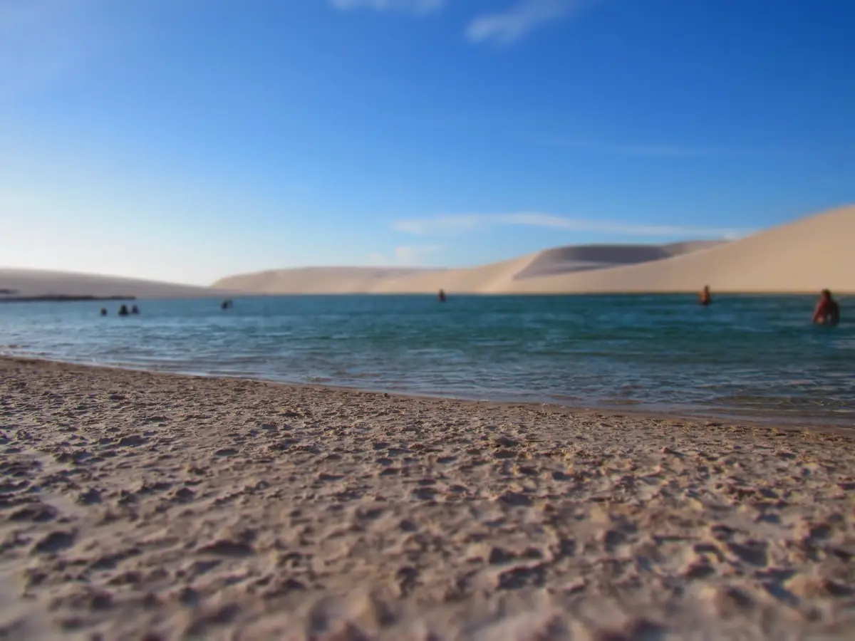 Banhistas na margem de areia da Lagoa Azul, com dunas ao fundo